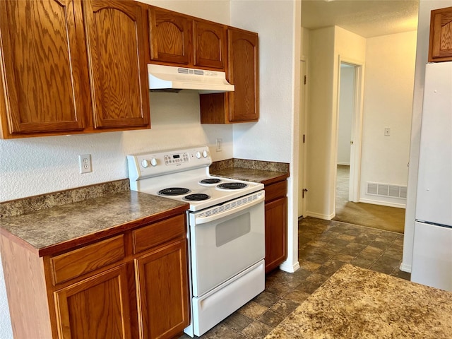 kitchen with visible vents, white appliances, baseboards, dark countertops, and under cabinet range hood
