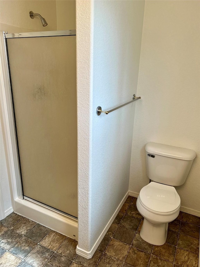 full bath with baseboards, toilet, and a stall shower