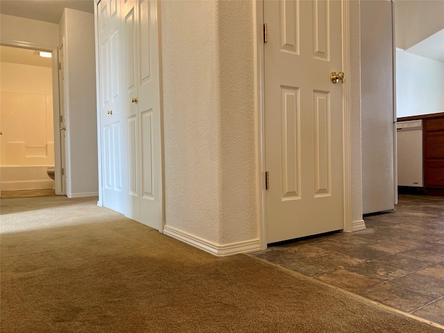 hall featuring baseboards and dark carpet