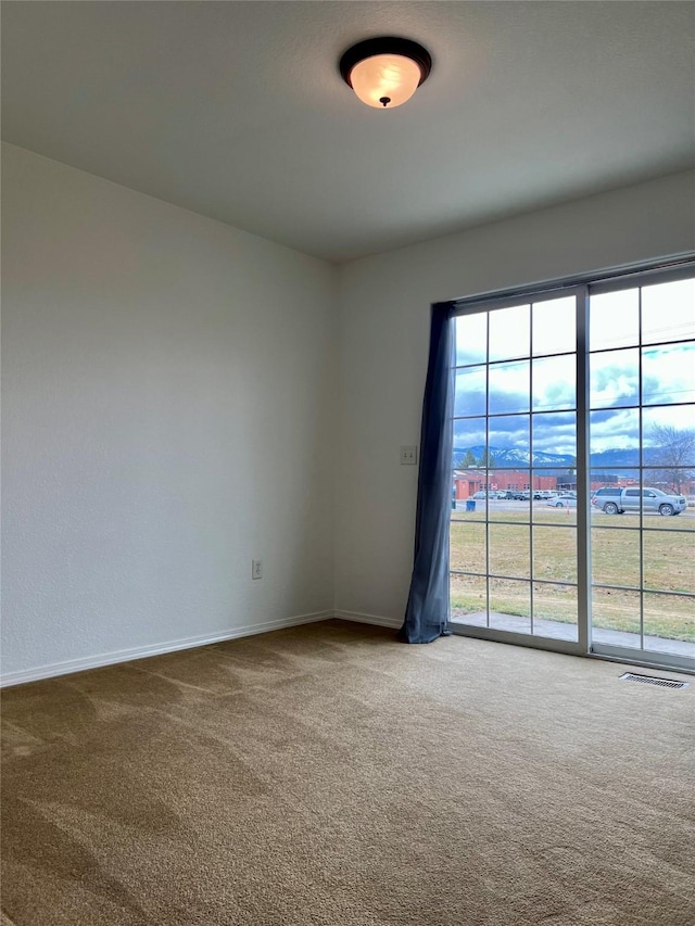 carpeted empty room featuring baseboards and visible vents