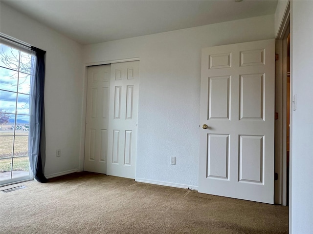 unfurnished bedroom featuring a closet, access to outside, baseboards, visible vents, and carpet