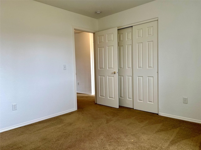 unfurnished bedroom featuring baseboards, carpet flooring, and a closet