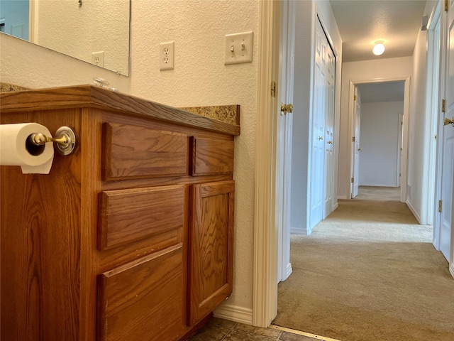 corridor featuring carpet floors, a textured wall, and baseboards