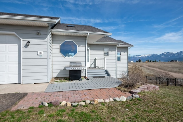 18 Mission View Dr, Polson, MT 59860 - rear view of property with fence, an attached garage, a mountain view, and a shingled roof