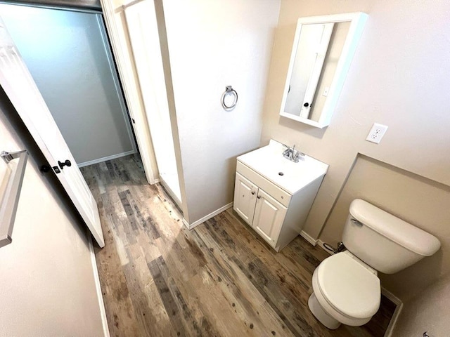 659-665 Logan St, Helena, MT 59601 - half bathroom featuring toilet, wood finished floors, baseboards, and vanity