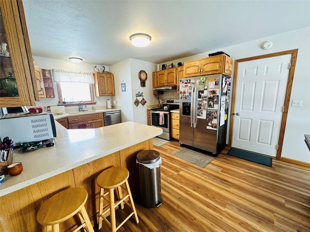 47 3rd Ave S, Stanford, MT 59479 - kitchen with stainless steel appliances, a sink, under cabinet range hood, light wood finished floors, and a peninsula