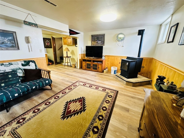 47 3rd Ave S, Stanford, MT 59479 - living room with a wainscoted wall, a wood stove, wooden walls, and light wood finished floors