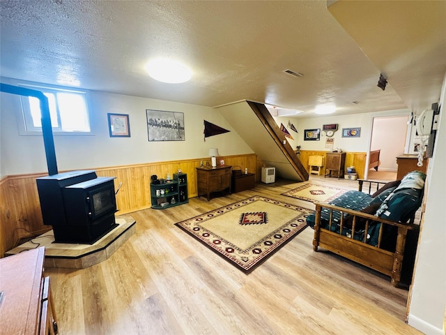 47 3rd Ave S, Stanford, MT 59479 - living area with a wood stove, light wood-style flooring, a textured ceiling, wainscoting, and wooden walls