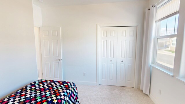 carpeted bedroom featuring baseboards and a closet