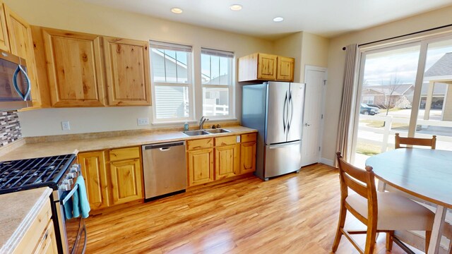 kitchen featuring light countertops, a sink, light wood-type flooring, and appliances with stainless steel finishes