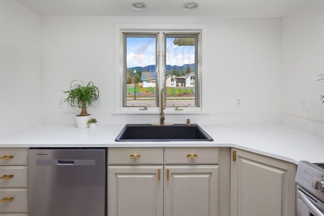 kitchen with light countertops, stainless steel dishwasher, a sink, and stove
