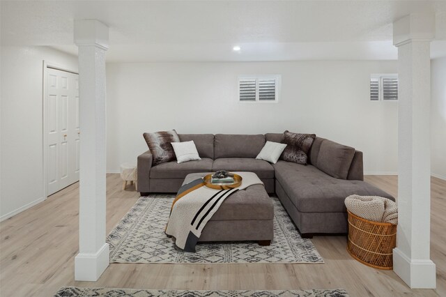 living area featuring visible vents, baseboards, ornate columns, and wood finished floors