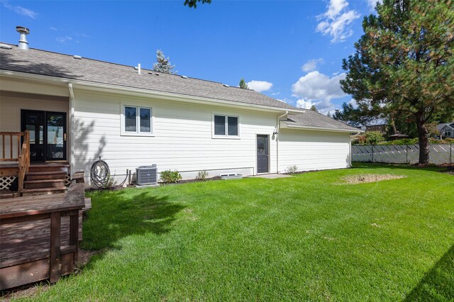 rear view of house featuring a yard, roof with shingles, central air condition unit, and fence