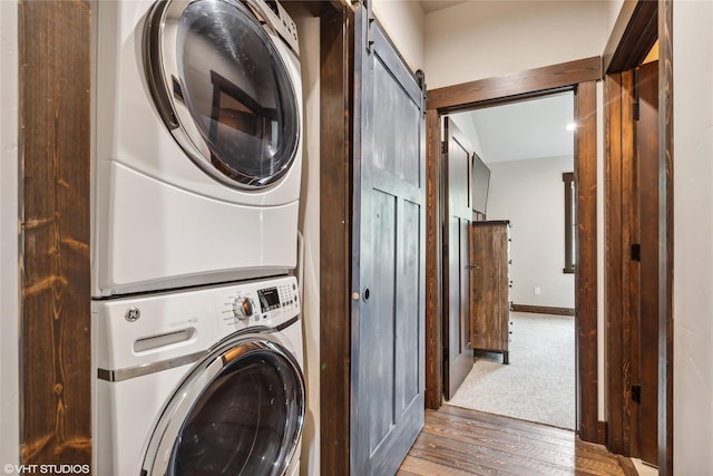 62 Wilderness Lodge Rd, Eureka, MT 59917 - laundry area featuring baseboards, a barn door, stacked washer / dryer, laundry area, and wood finished floors