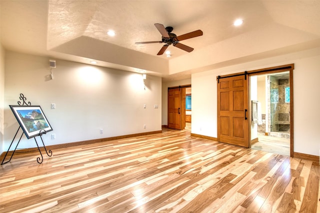 NHN Bears Rd, Stevensville, MT 59870 - unfurnished bedroom featuring light wood finished floors, baseboards, a raised ceiling, a barn door, and ensuite bath