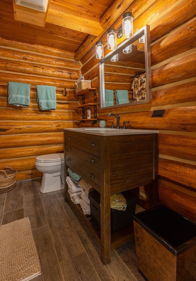 587 Cozy Ln, Helmville, MT 59843 - bathroom featuring log walls, toilet, wood finished floors, vanity, and wood ceiling