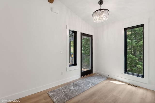 34 Grizzly Ct, Bigfork, MT 59911 - doorway to outside featuring wood finished floors, a chandelier, and baseboards