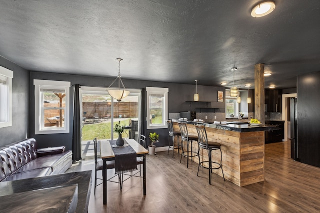 4528 Adellon Ct, Stevensville, MT 59870 - kitchen with a breakfast bar area, dark countertops, dark wood-style floors, a kitchen island, and a textured ceiling