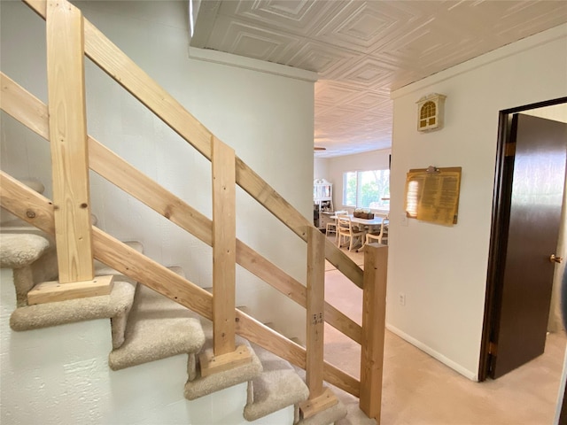 staircase with baseboards, carpet flooring, and an ornate ceiling