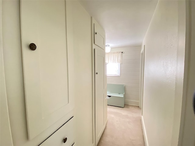 corridor featuring light colored carpet and baseboards