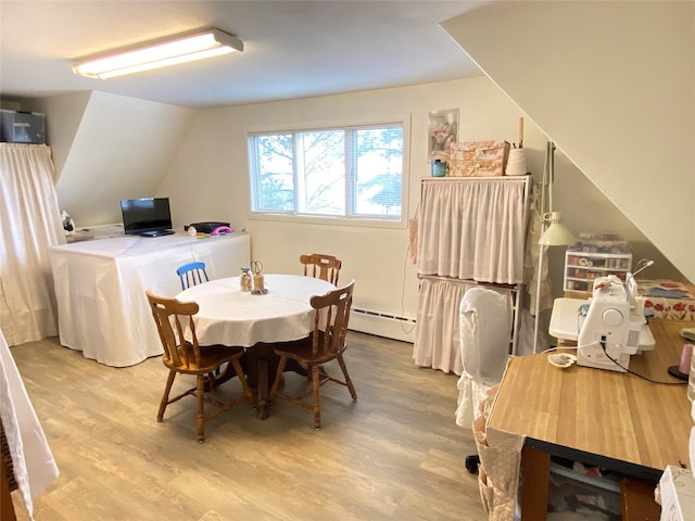 dining room with baseboard heating, wood finished floors, and vaulted ceiling