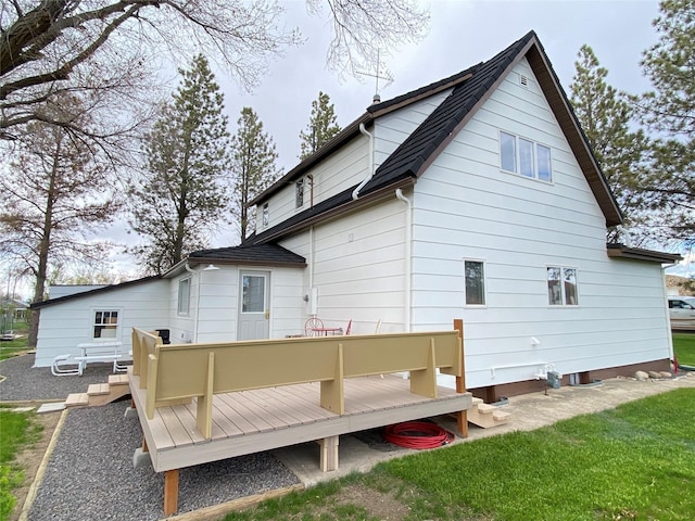 back of property featuring a lawn, a shingled roof, and a deck