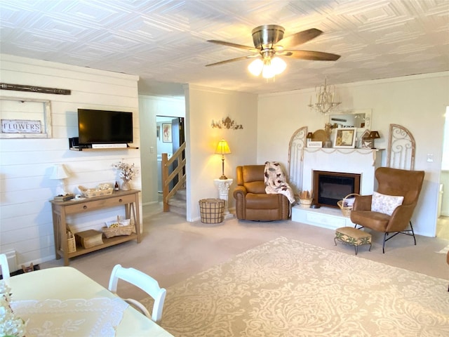 living area with a ceiling fan, a glass covered fireplace, an ornate ceiling, and stairs