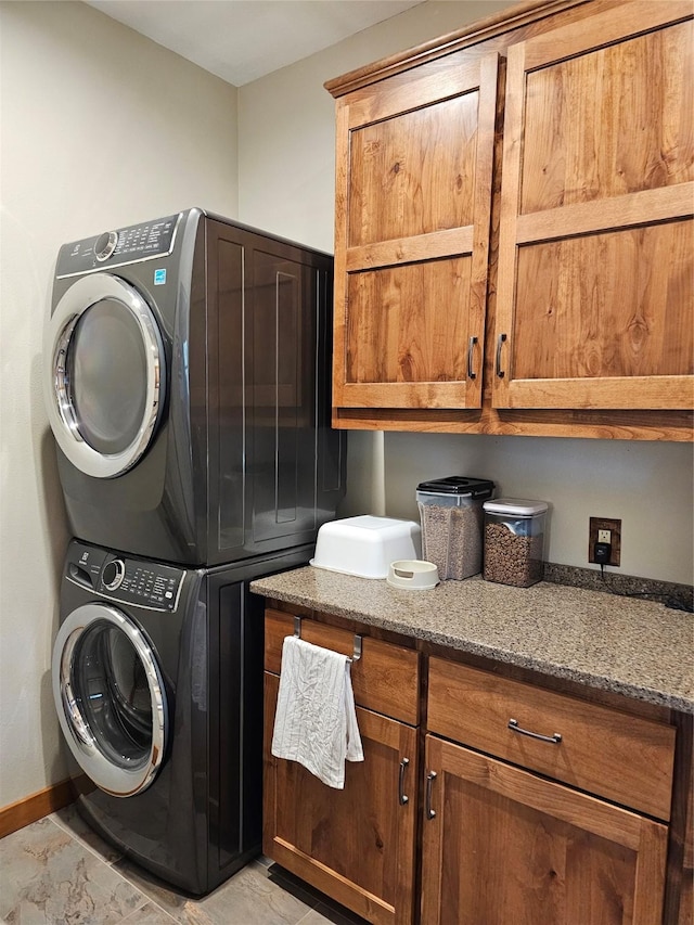 laundry area with cabinet space, stacked washer and dryer, and baseboards