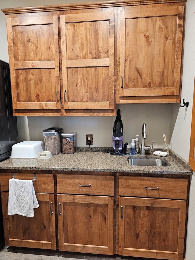 kitchen with brown cabinets, a sink, and stone counters