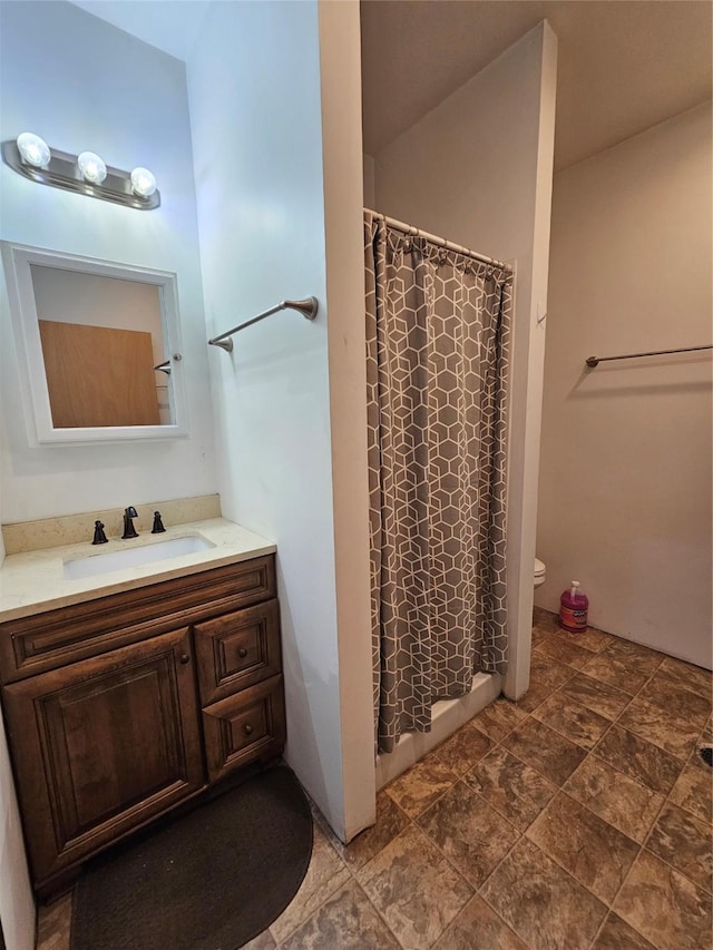 full bath featuring curtained shower, stone finish flooring, toilet, and vanity
