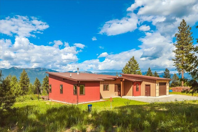 563 Riding High Dr, Eureka, MT 59917 - back of house featuring a mountain view, board and batten siding, driveway, and an attached garage