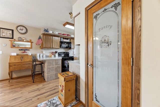 2804 Harmony Ct, Missoula, MT 59801 - kitchen with black appliances, light wood-style flooring, light countertops, a breakfast bar area, and a peninsula