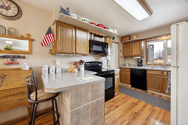 2804 Harmony Ct, Missoula, MT 59801 - kitchen with black appliances, light wood-style floors, a peninsula, light countertops, and a breakfast bar