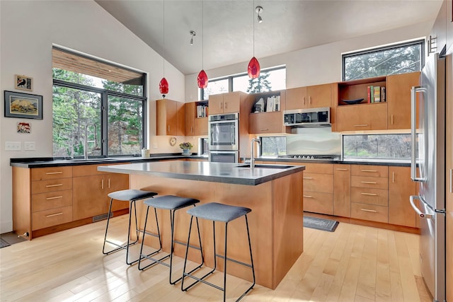 kitchen featuring appliances with stainless steel finishes, a sink, open shelves, and dark countertops