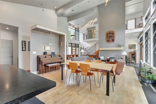 dining space featuring light wood finished floors, a high ceiling, and a healthy amount of sunlight