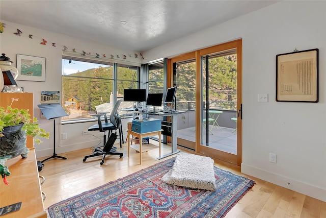 home office with baseboards and wood finished floors