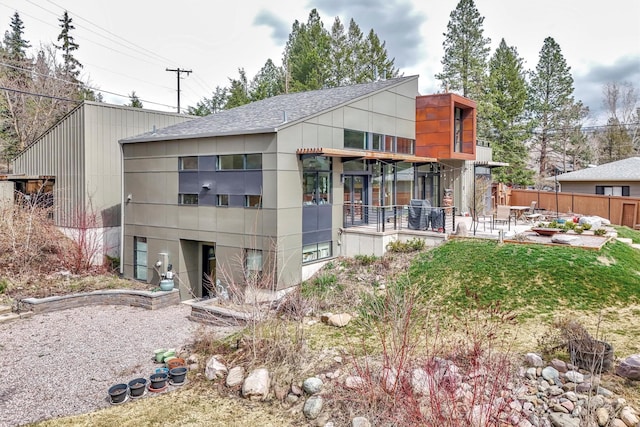 rear view of house featuring fence, a patio, and roof with shingles