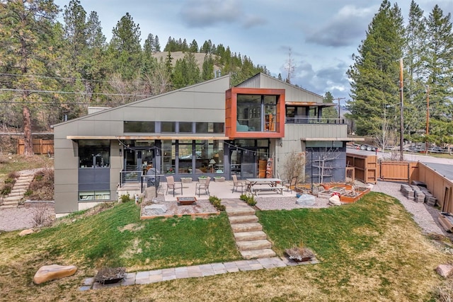 rear view of house featuring a patio, a balcony, fence, and a lawn