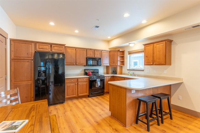 402 Sperry Ct, Whitefish, MT 59937 - kitchen with black appliances, a peninsula, light wood-style flooring, brown cabinetry, and recessed lighting