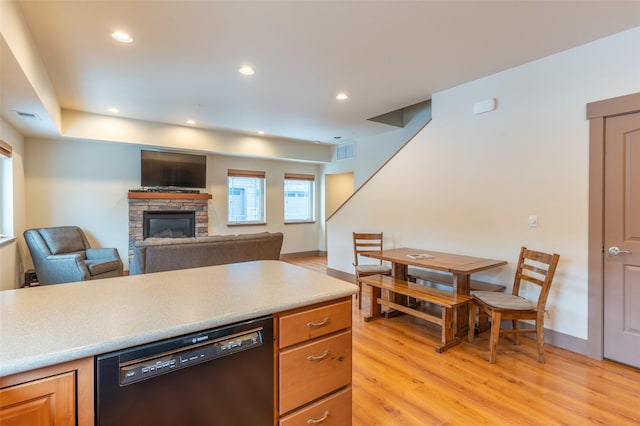 402 Sperry Ct, Whitefish, MT 59937 - kitchen featuring dishwasher, light wood-style flooring, a fireplace, light countertops, and brown cabinetry