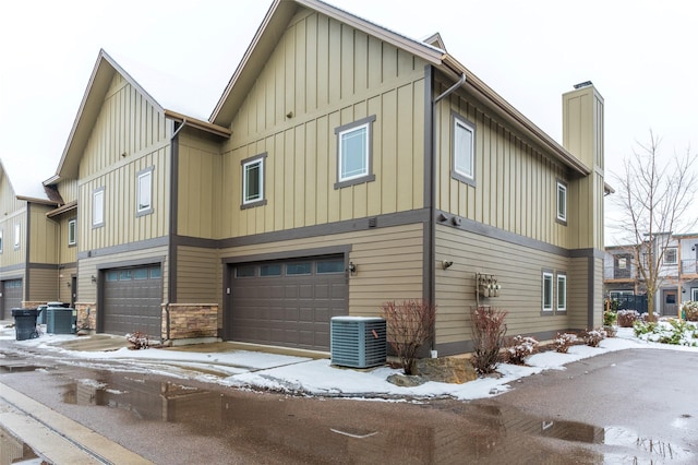 402 Sperry Ct, Whitefish, MT 59937 - view of snow covered exterior featuring board and batten siding, an attached garage, and a chimney