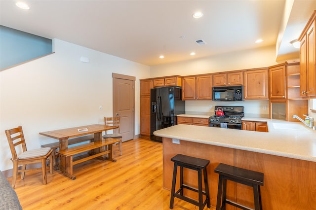402 Sperry Ct, Whitefish, MT 59937 - kitchen featuring black appliances, light countertops, a peninsula, light wood-style flooring, and recessed lighting