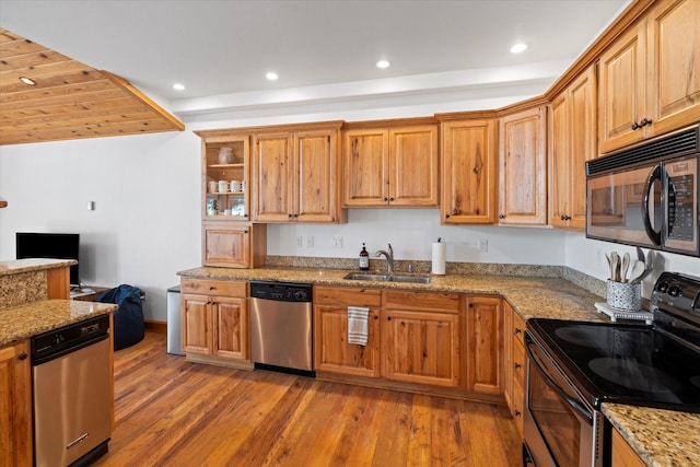 kitchen featuring light stone counters, appliances with stainless steel finishes, a sink, light wood-style floors, and recessed lighting