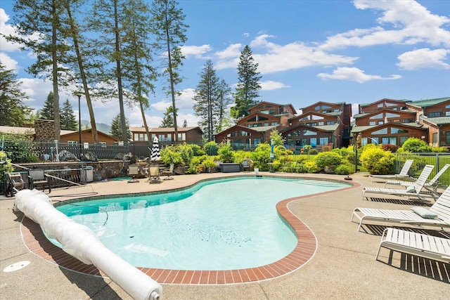 pool featuring a patio, fence, and a residential view