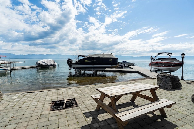 view of dock with a patio, a water view, a fire pit, and boat lift