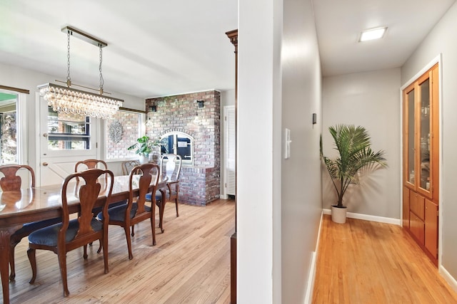 dining room featuring baseboards, light wood-style floors, and a chandelier
