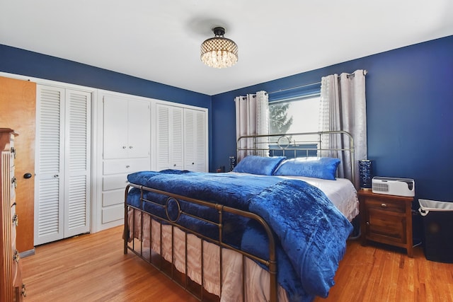 bedroom featuring a notable chandelier, wood finished floors, and two closets