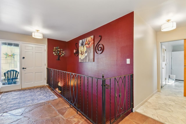entryway with stone finish floor, baseboards, and an accent wall