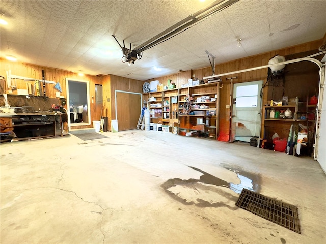 garage featuring electric panel, wood walls, and a garage door opener