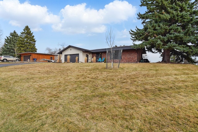 view of front of house with a front yard, a garage, and brick siding